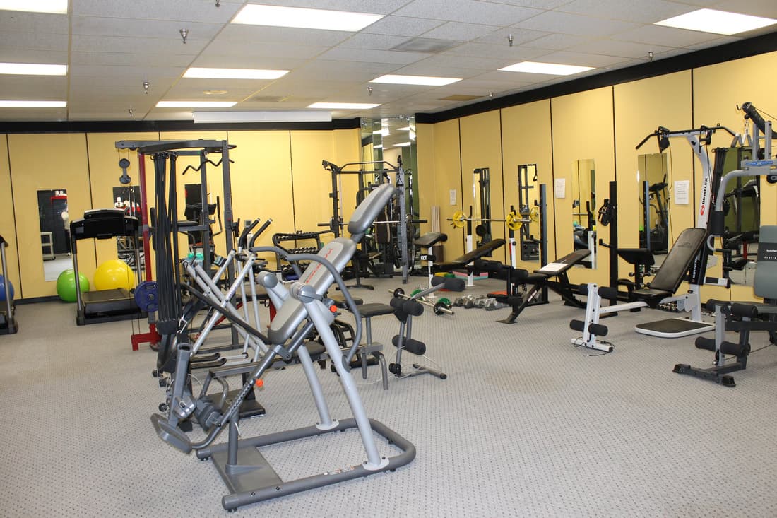 Equipment room at the CWC Gym, including free weights, benches, and cable machines